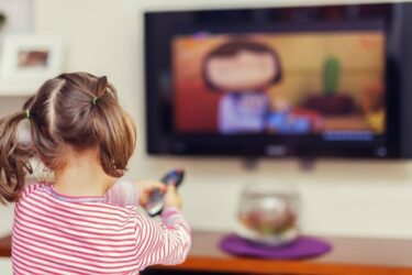 child sitting down and watching television program.